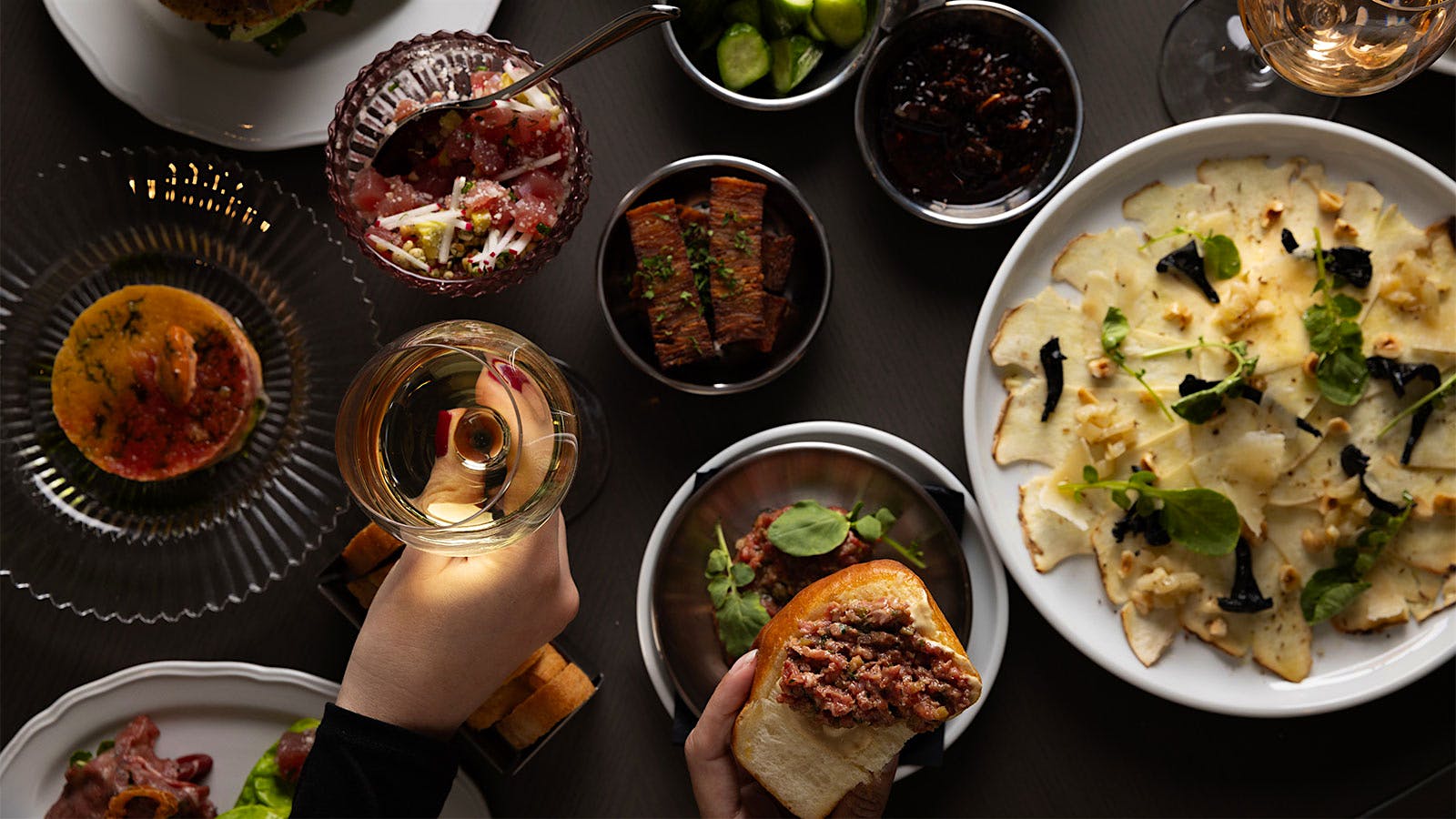 A selection of appetizers from Vermilion Club in Boston, like steak and tuna tartare, served with glasses of wine.